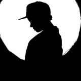 Artistic silhouette of a person with cap against a glowing full moon backdrop.